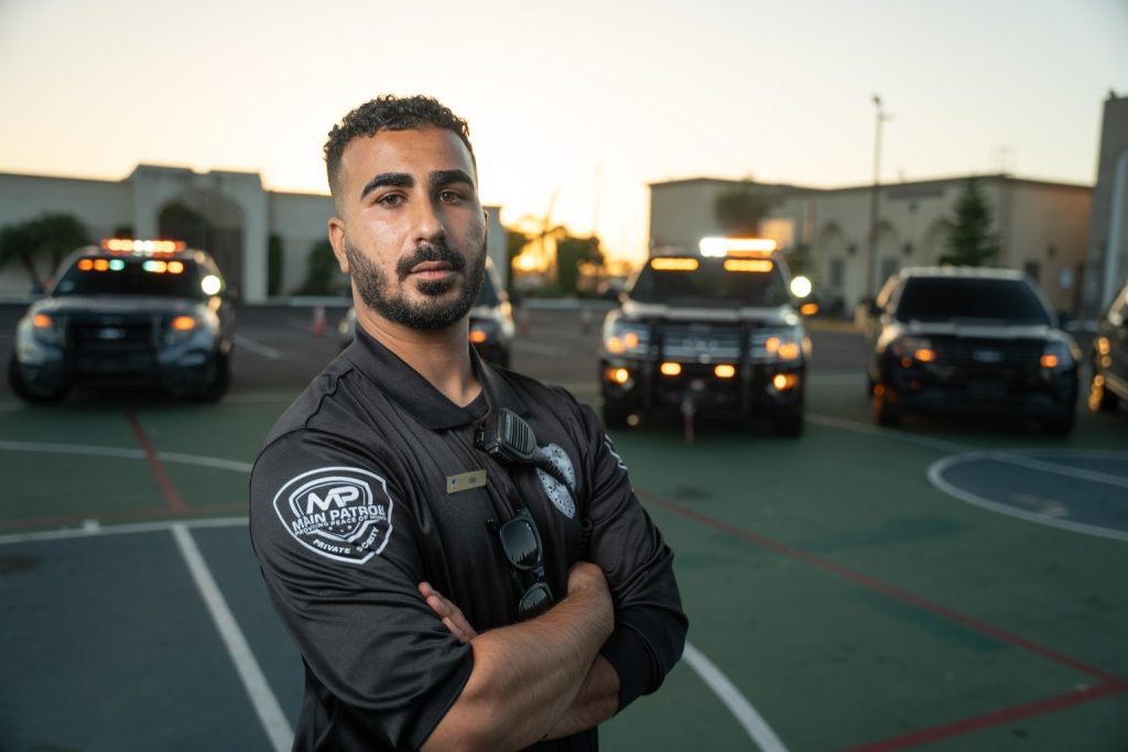 Main Patrol officer with arms crossed in front of patrol vehicles