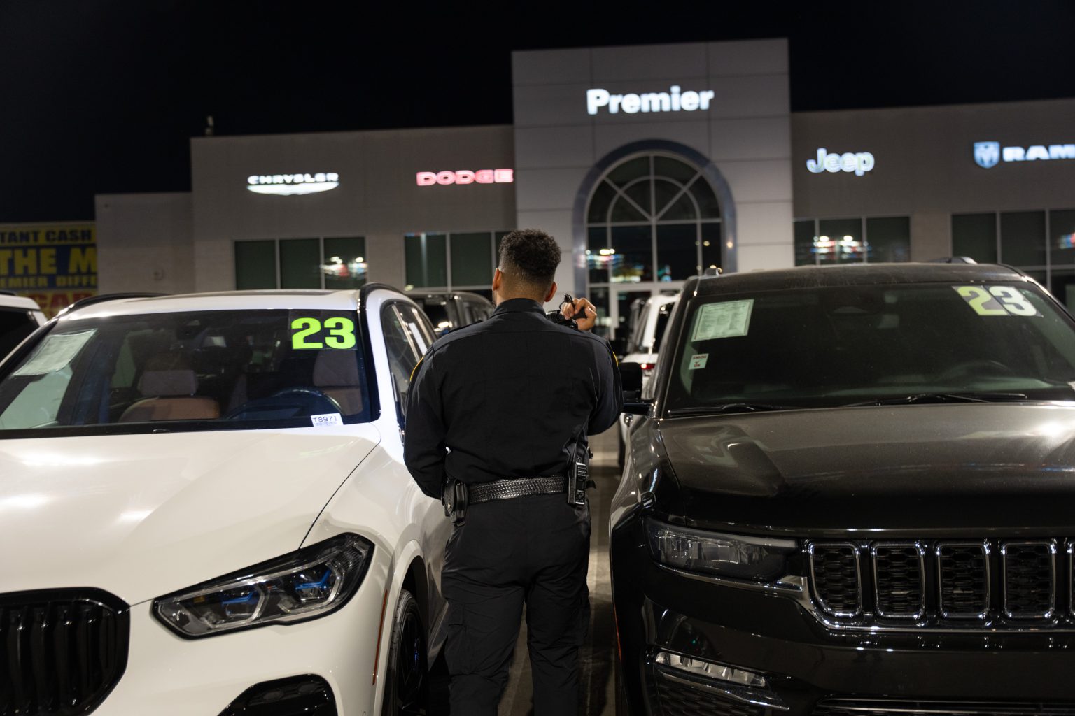 Main Patrol officer inspecting vehicles at a dealership at night