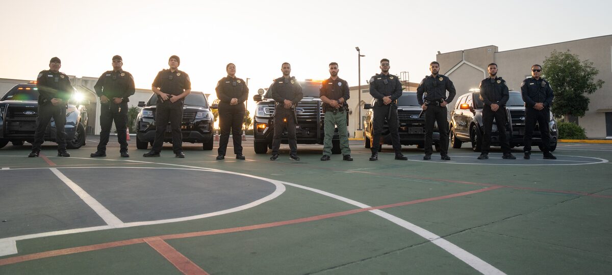 The Main Patrol team standing in front of marked patrol vehicles at sunset